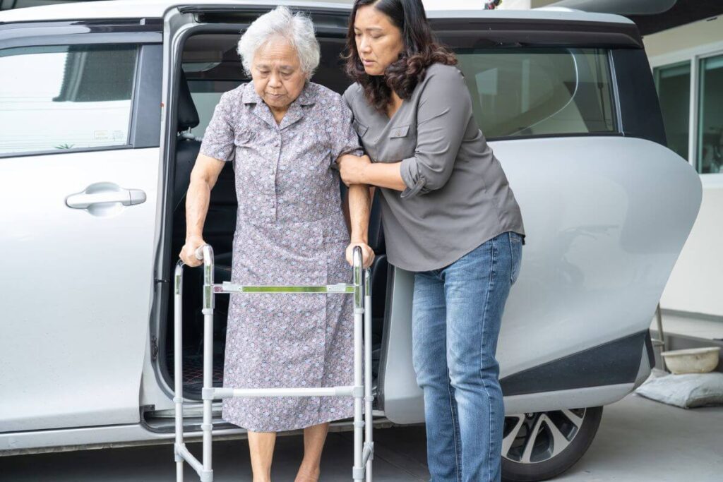 an adult child assists her elderly mom out of a specialized transportation van after figuring out what to do when an elderly parent can't walk
