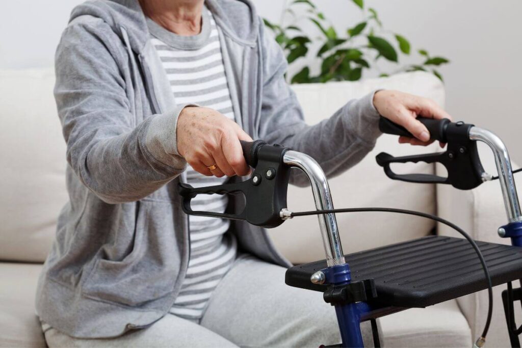 an elderly woman prepares to use an mobility device with a seat and a walker to help get off the sofa and move to another room
