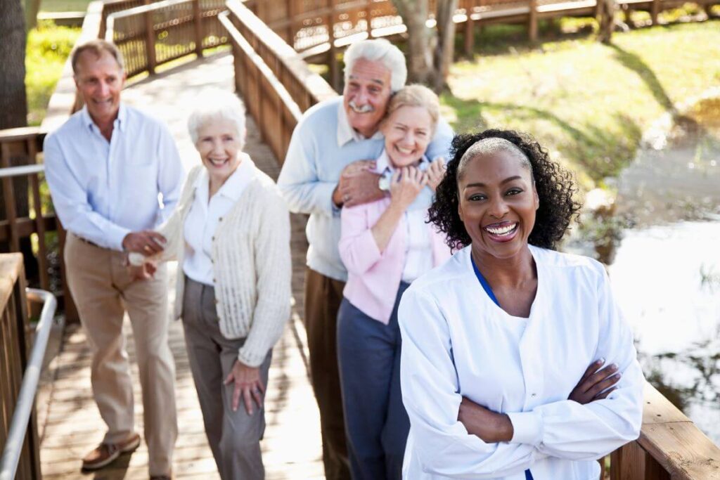 two couples who live at an assisted living facility take a walk on the grounds with a caregiver