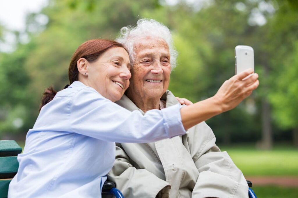 a middle aged woman who provides respite care for families who are feeling trapped caring for elderly parents takes a selfie with her elderly companion