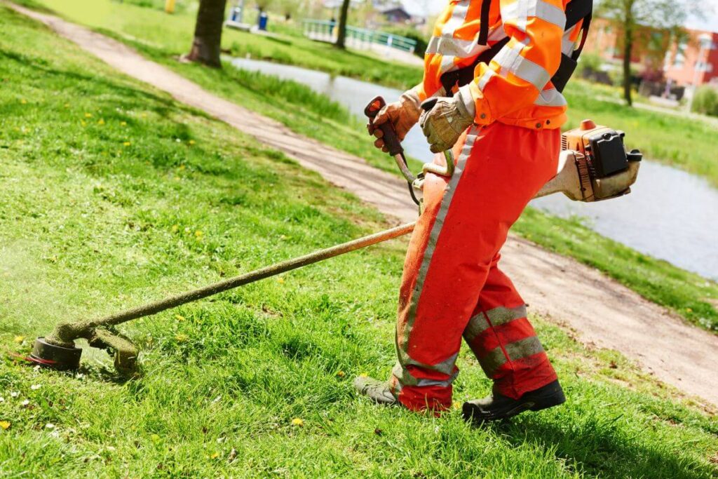 man in orange work clothes works on the lawn of an elderly couple