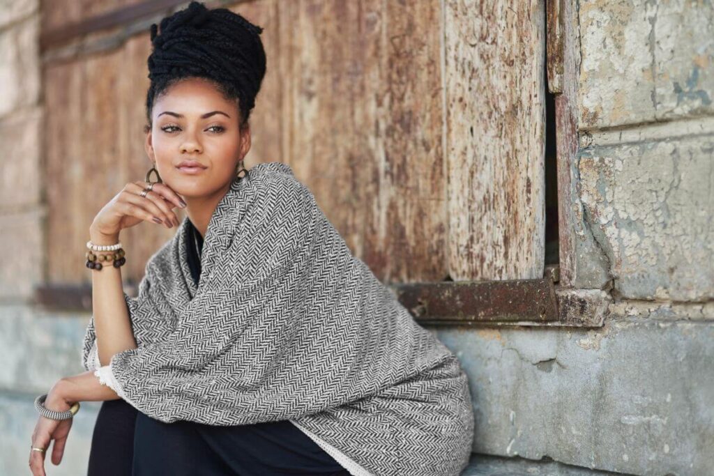 a beautiful black women sits against the side of a wooden building and ponders finding purpose in life after 50