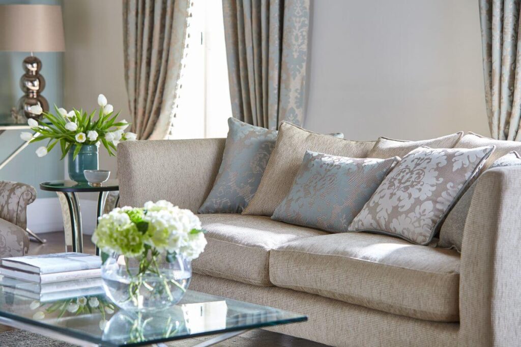 a beautiful living room decorated in soft beiges and blues with fresh white flowers makes a comfortable setting for midlife and beyond