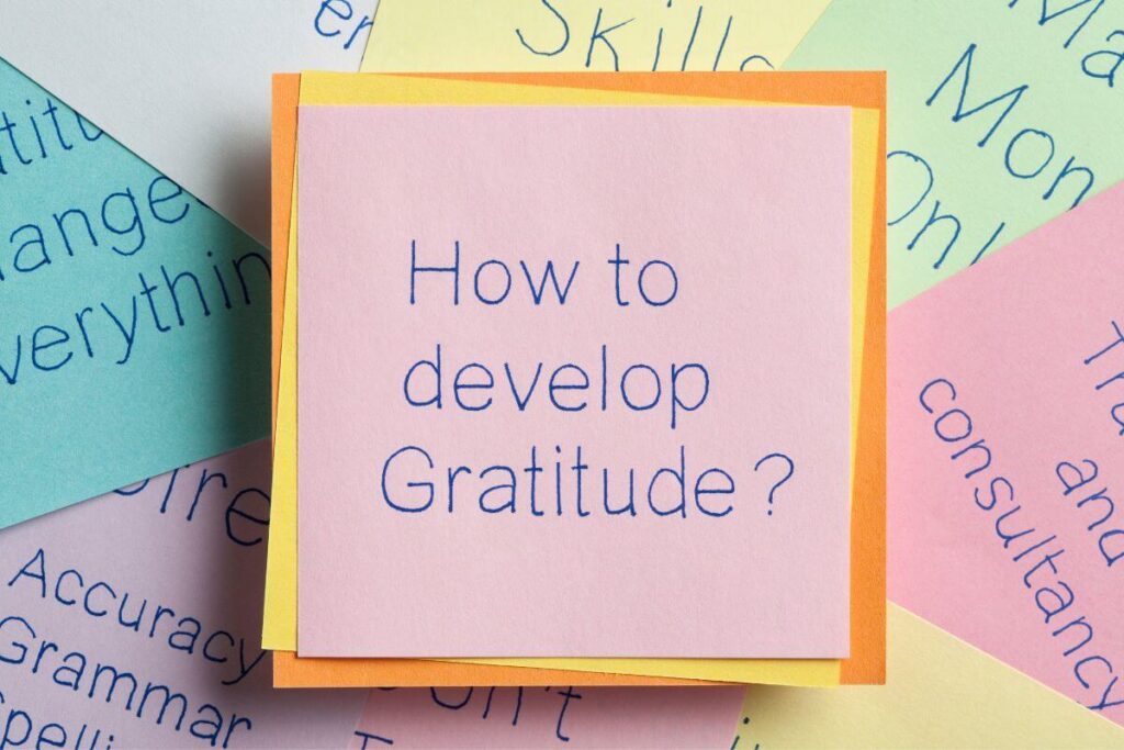 sticky notes laying in a pile with the top one saying how to develop gratitude?
