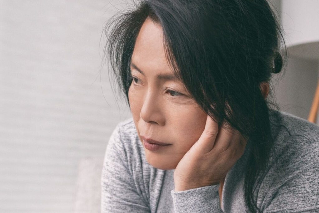 close up of a middle aged Asian woman who seems anxious or depressed