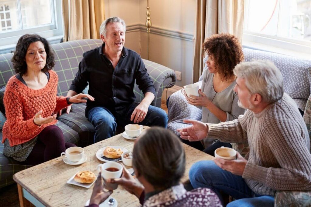 a group of 5 diverse men and women enjoy a small social gathering