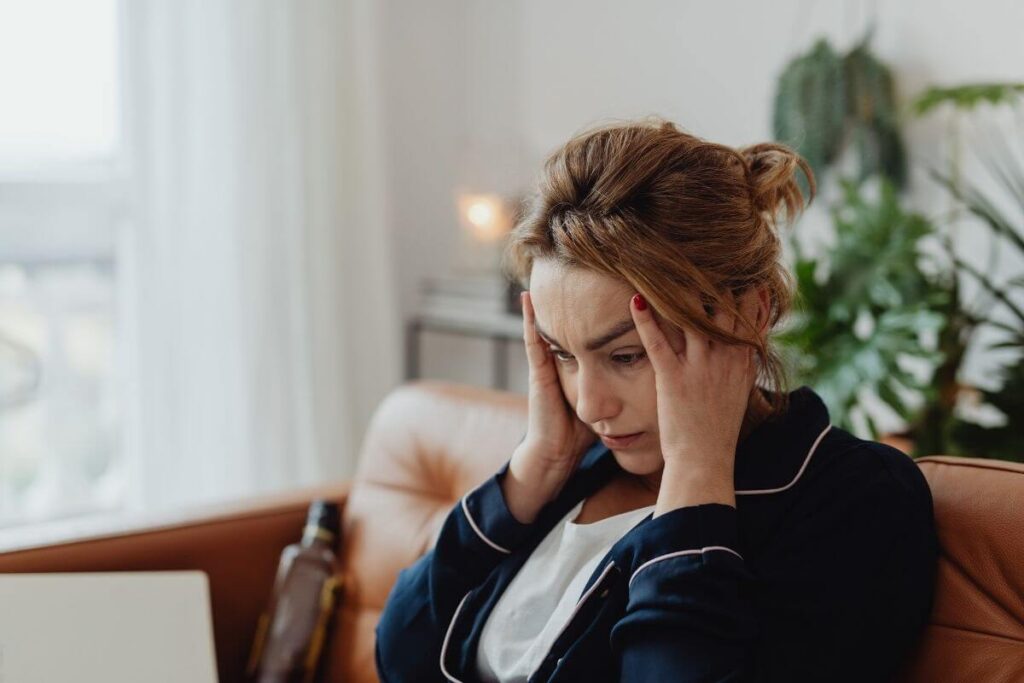 an anxious middle aged woman holds her temples as she thinks about a social event coming up