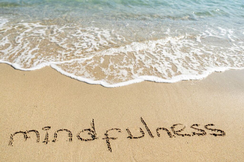 a beach with mindfulness written in the sand