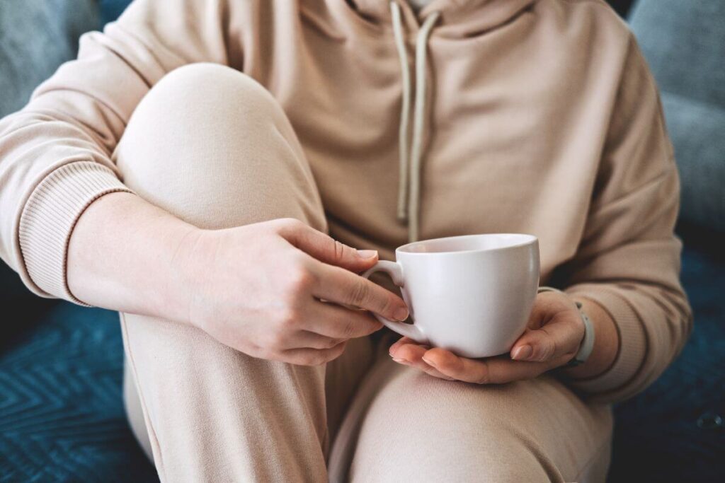 close up of a female in comfortable clothes relaxing with a cup of tea