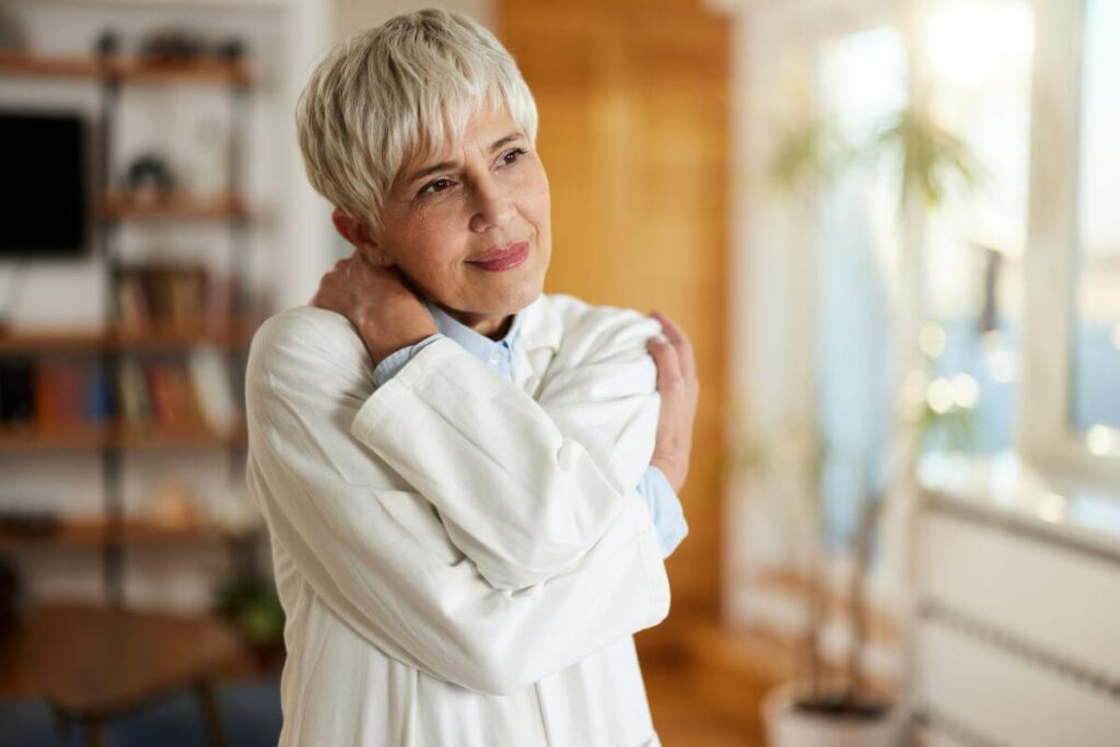 a middle-aged woman hugs herself as a symbol of self love and self compassion