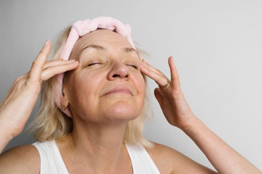 a middle-aged woman cleanses her face as part of her self care practices