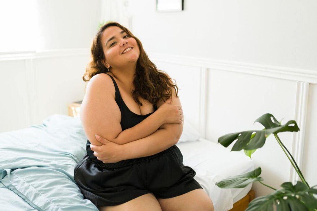 a beautiful young woman gives herself a hug as she learns how to start your self love journey