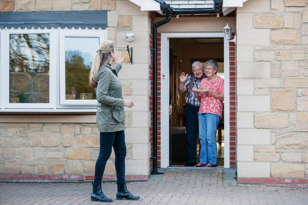 grandparents and adult child saying goodbye at the front door of home where everyone feels peace of mind because the home has been made safe
