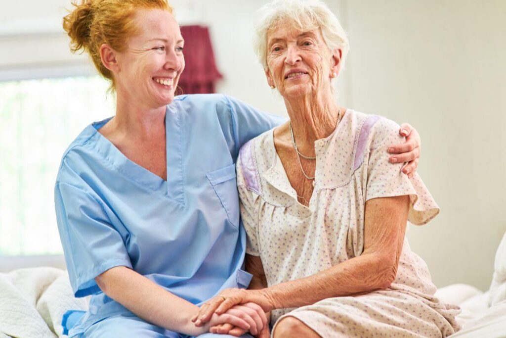 a hospice nurse and patient sit together on the edge of the bed