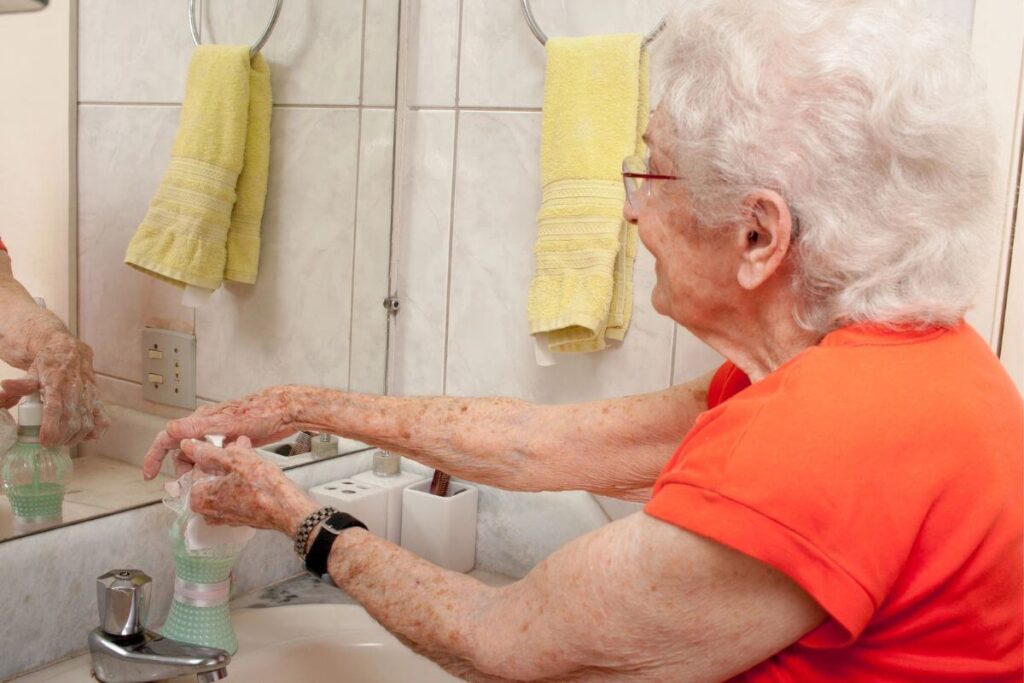 senior woman at the bathroom sink washing her hands for personal hygiene