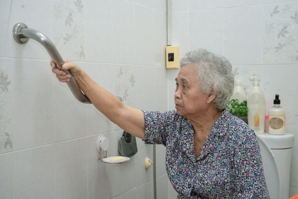 elderly women on the toilet reaches for the grab bar to get up