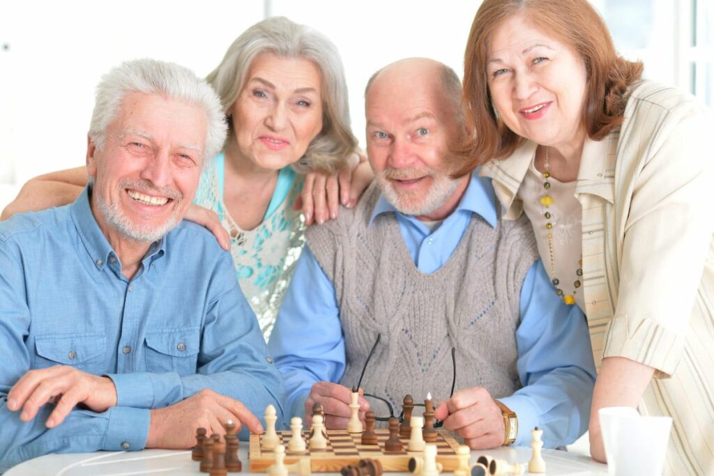 four senior citizens enjoy a game of backgammon