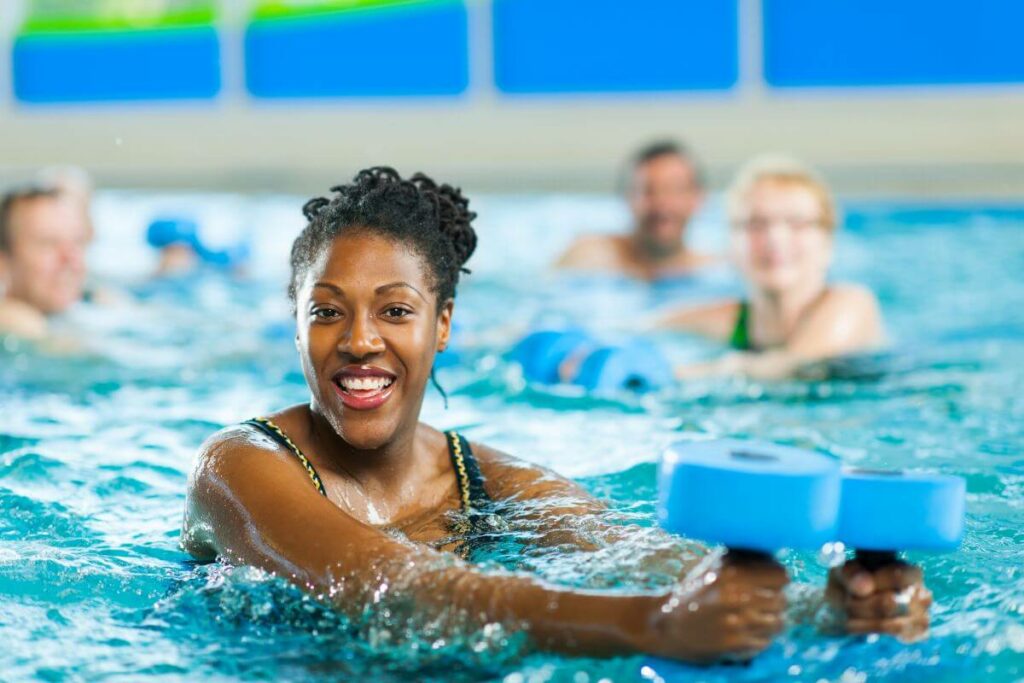 middle aged woman exercising in an indoor swimming pool with others in the background