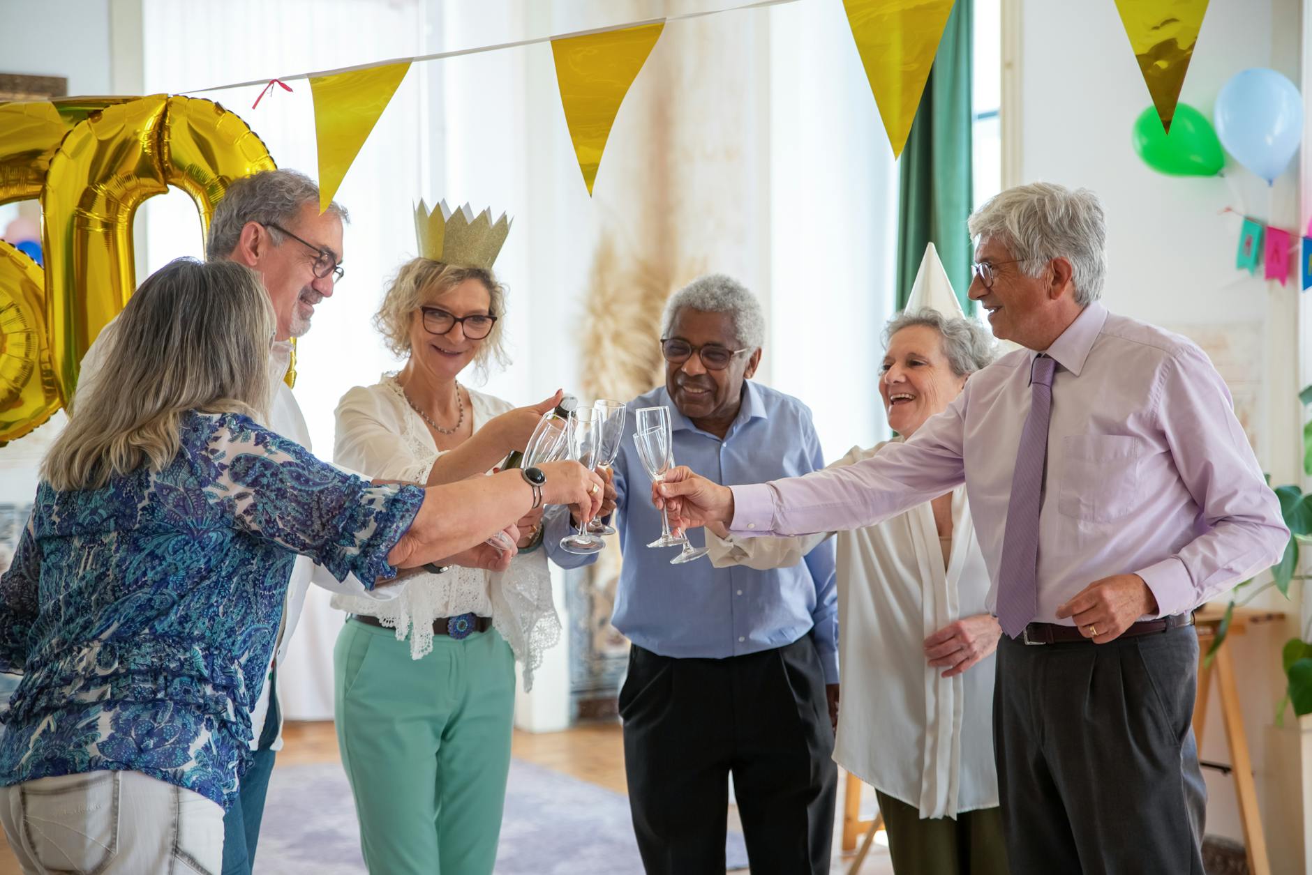 A group of elderly friends celebrating a birthday in Portugal with champagne and decorations.Kampus Production