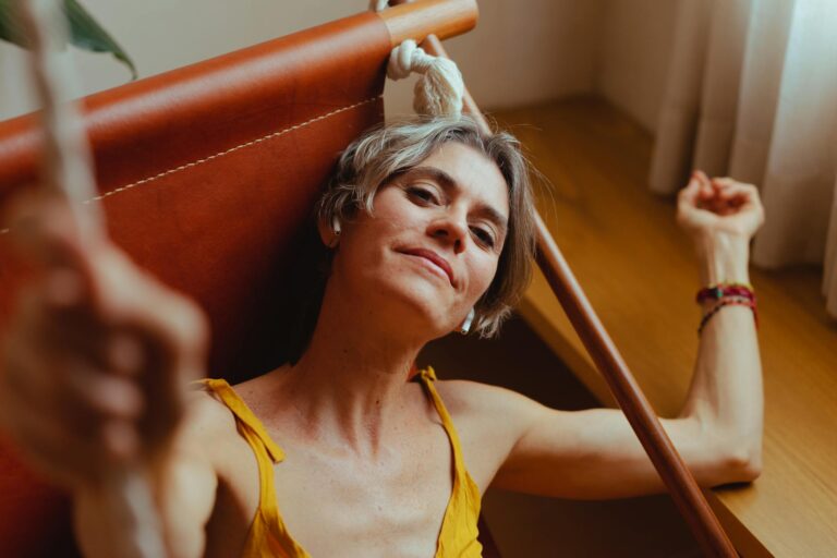 A senior woman relaxes on a hammock indoors, embodying calm and contentment.