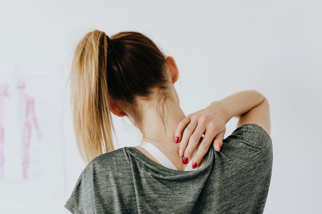 A_woman_in_casual_clothing_holds_her_neck,_indicating_pain_or_discomfort..Photo_By__Kaboompics.com