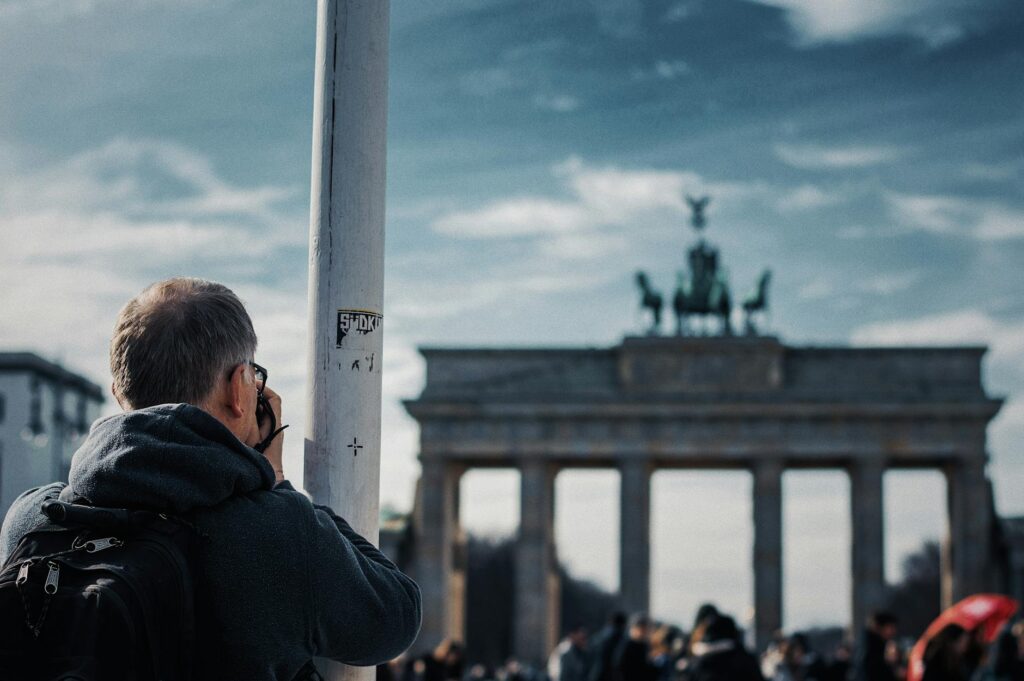 Tourist photographing the iconic Brandenburg Gate in Berlin, Germany during the day.