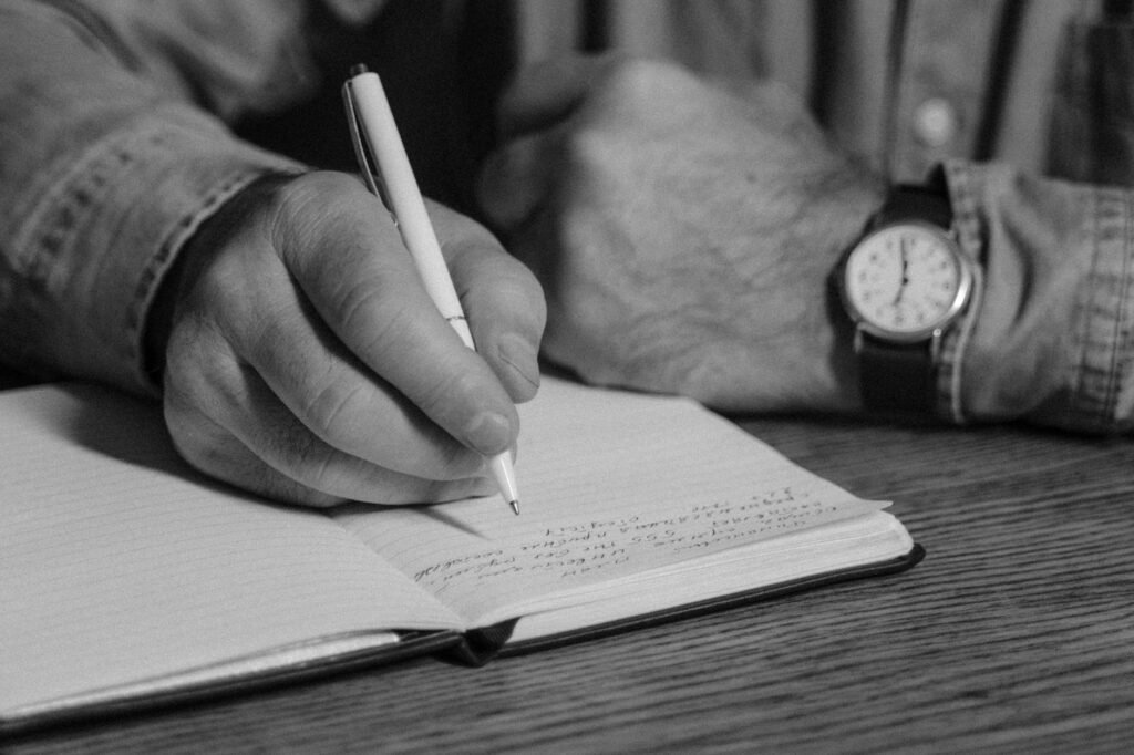 Black-and-white_close-up_of_person_writing_in_a_notebook,_emphasizing_handwriting_and_detail..Tima_Miroshnichenko