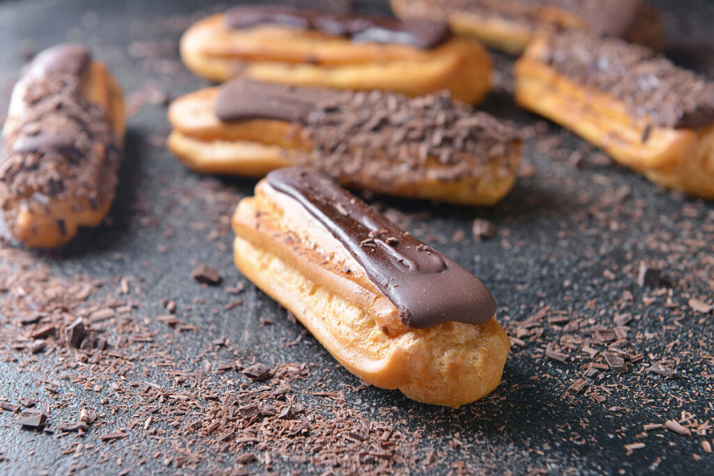 Tasty chocolate eclairs on dark background
