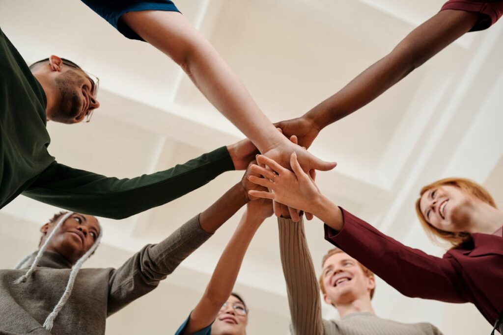 People Putting Hands Together in Act of Motivation and Smiling