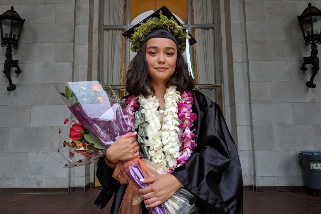 Woman in Graduation Gown and Cap Holding Bouquets of Flowers