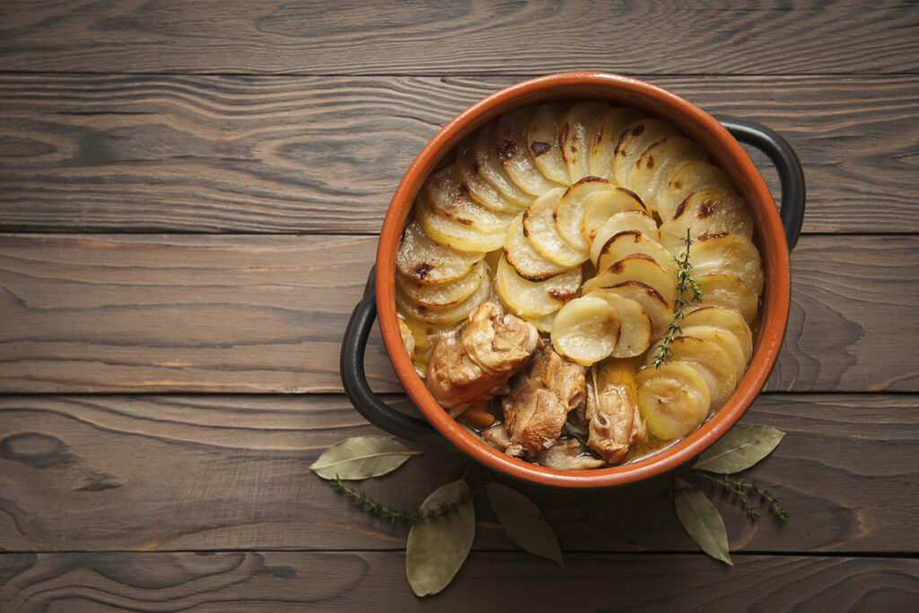 Homemade Lancashire hotpot on wooden background - a stew consists of lamb, onion, carrot, Worcestershire sauce, topped with sliced potatoes, bay leaves, thyme and baked in a heavy pot on a low heat.