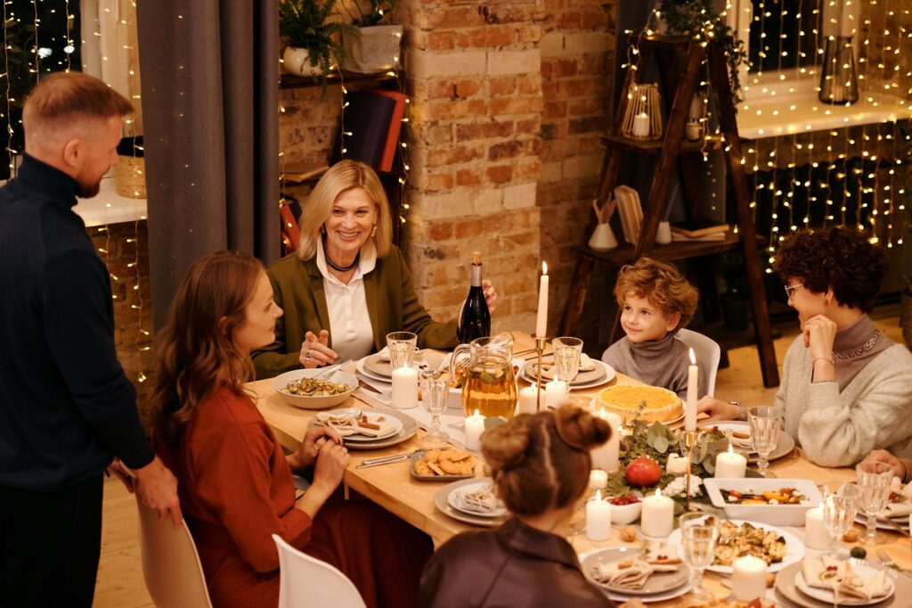 Warm family gathering enjoying Christmas dinner with festive decor and lights.