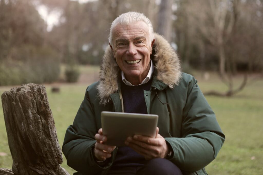 Adult Man Wearing Green Jacket Holding a Tablet