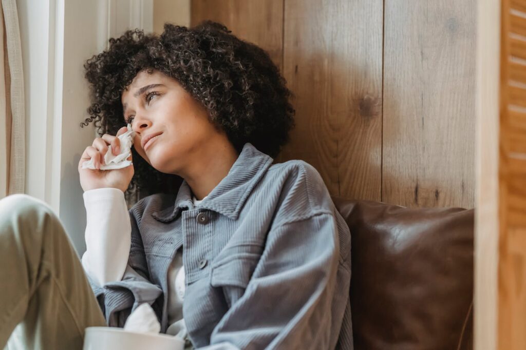 Upset black woman wiping tears with tissue
