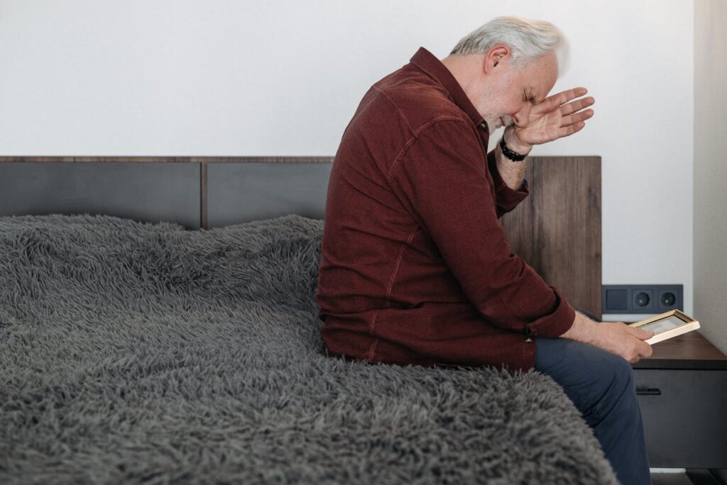 An Elderly Man Crying while Holding a Picture Frame