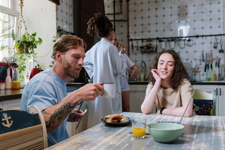 Woman and Man Sitting by Table and Eating Breakfast