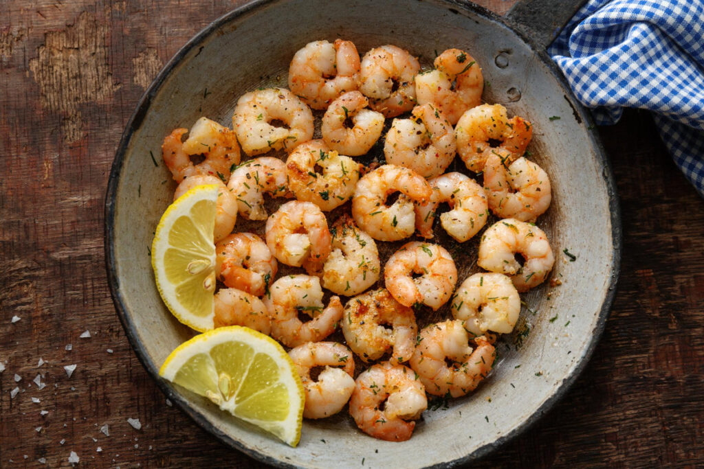 Tasty appetizing fried shrimps on pan on dark stone background. Top View.
