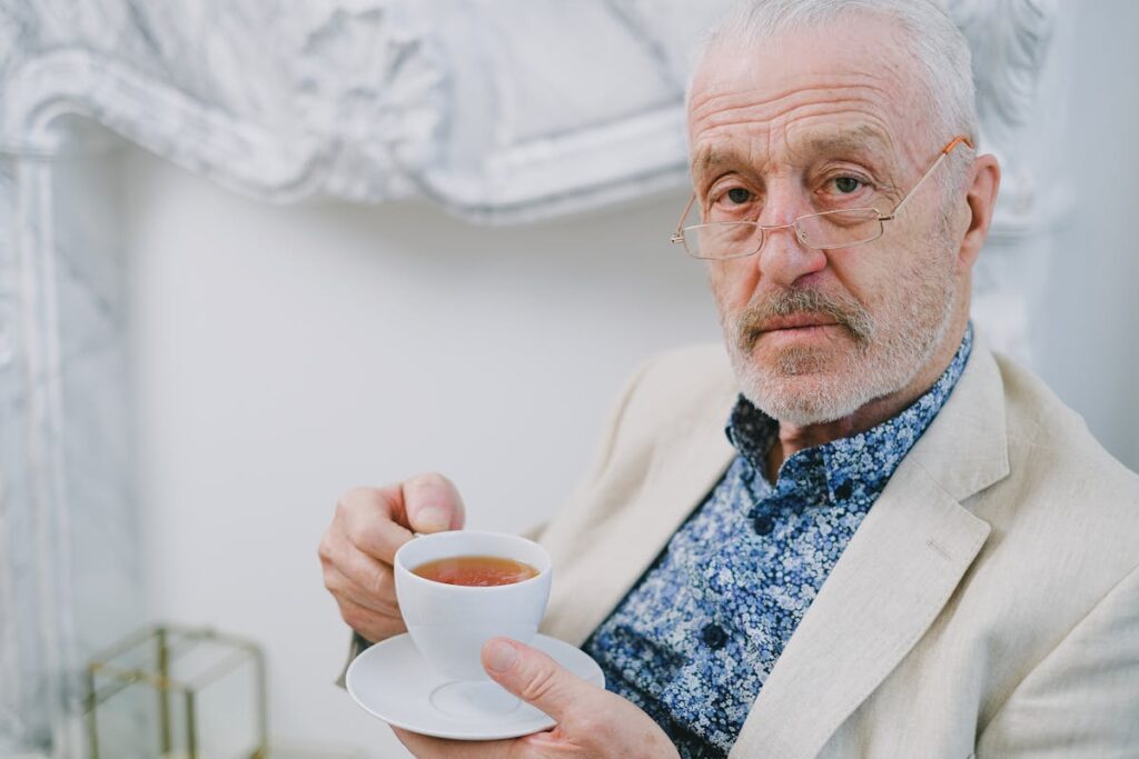 Elderly Man with Sunglasses Holding a White Cup with Tea