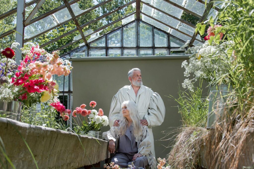 Senior_couple_in_a_greenhouse_filled_with_colorful_flowers,_showcasing_floral_beauty_and_serenit
