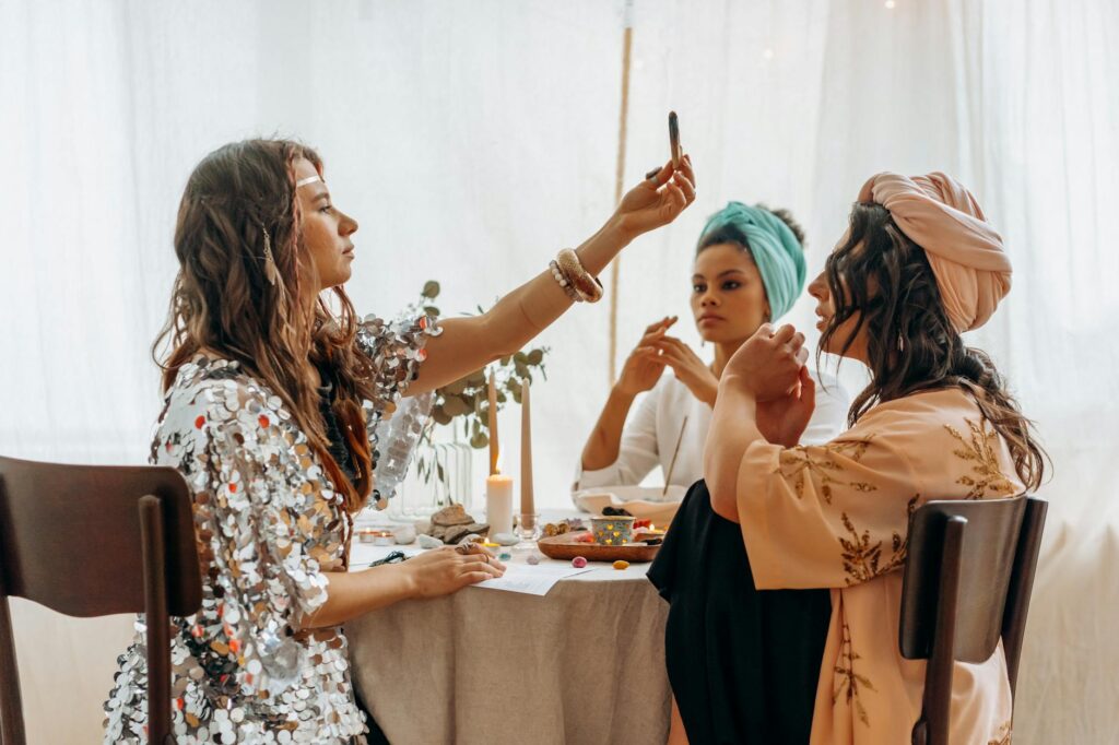Three women performing a spiritual healing ritual at a decorated table indoors.