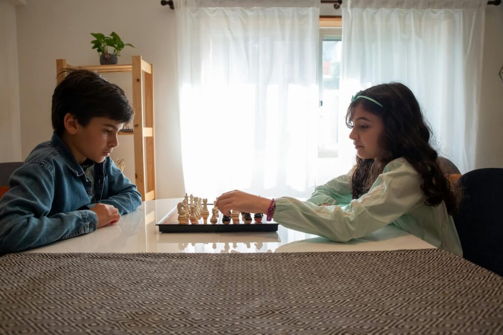 Two children engaged in a chess game indoors, captured in Portugal.