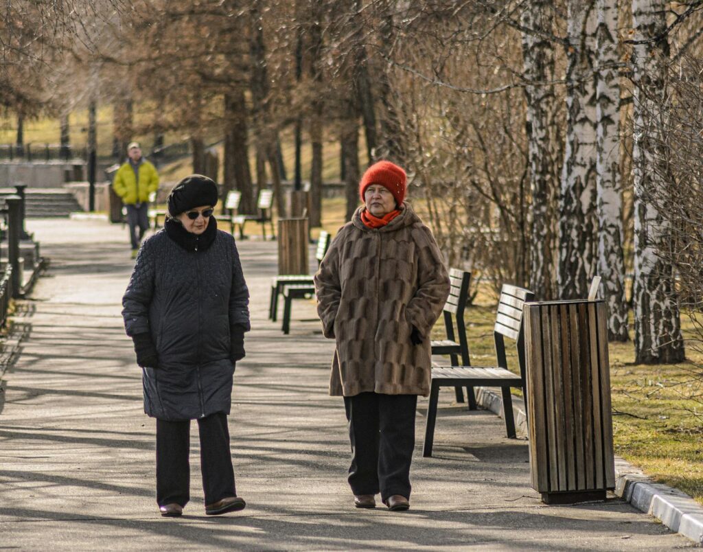 Two senior women stroll in an outdoor park on a sunny early spring day.Radik 2707