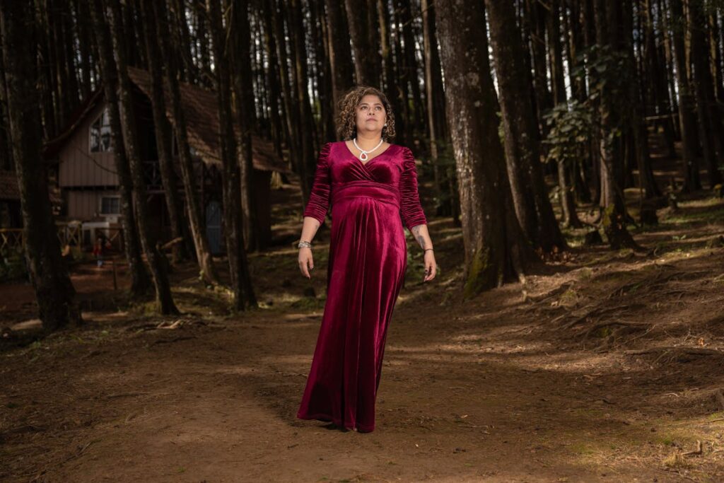 Model in a Purple Long Dress Near a Cabin in the Forest