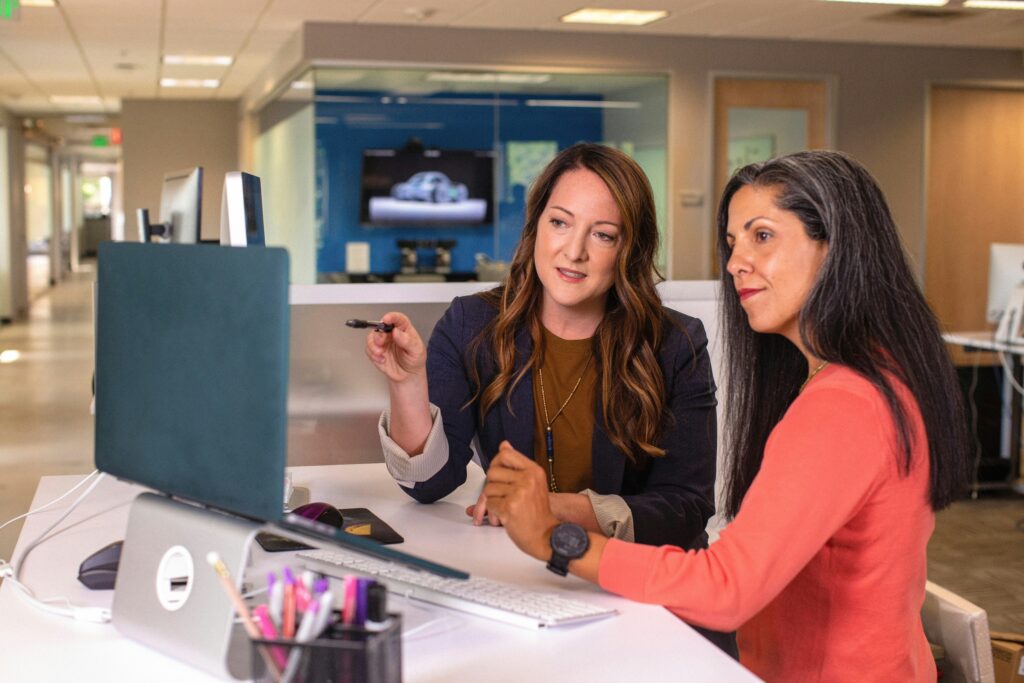two_women_sitting_at_a_table_looking_at_a_computer_screen.LinkedIn_Sales_Solutions