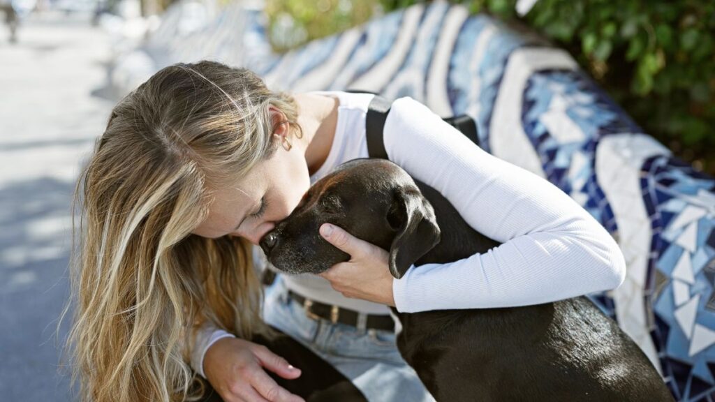 woman hugging and kissing dog outside