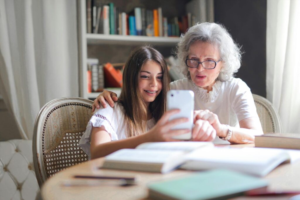 A grandmother and granddaughter bonding over a smartphone at home showcasing generational connection.Andrea Piacquadio