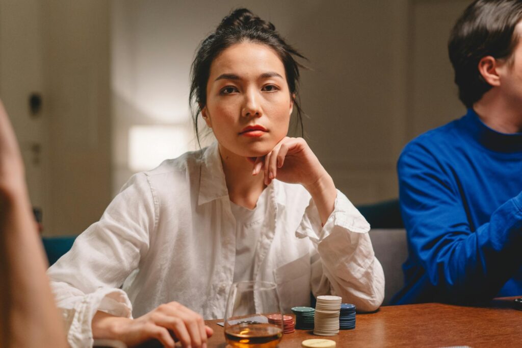 A thoughtful woman contemplating her next move at a poker game indoors.