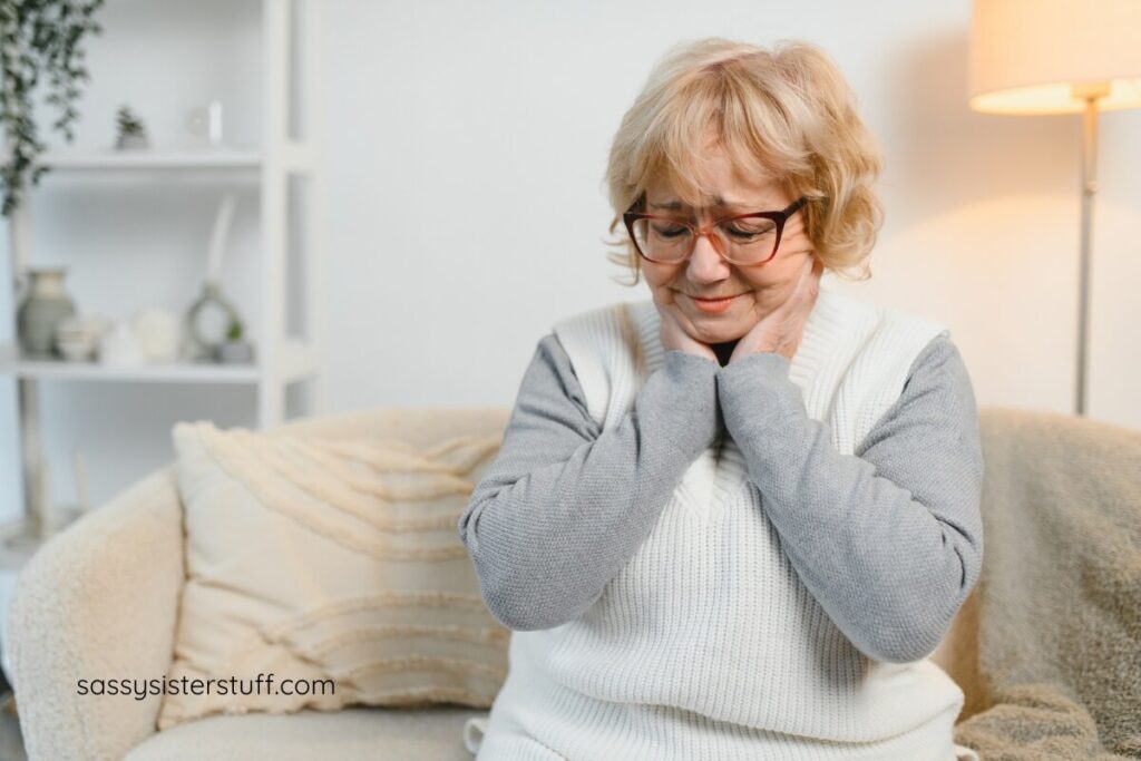 woman sitting on sofa holding her neck where lymph nodes are causing her chronic pain.