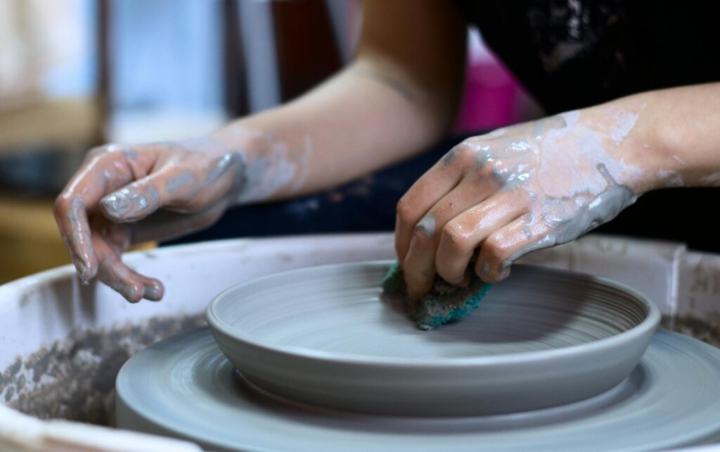 Close-up of hands shaping pottery clay on a spinning wheel in a creative studio.