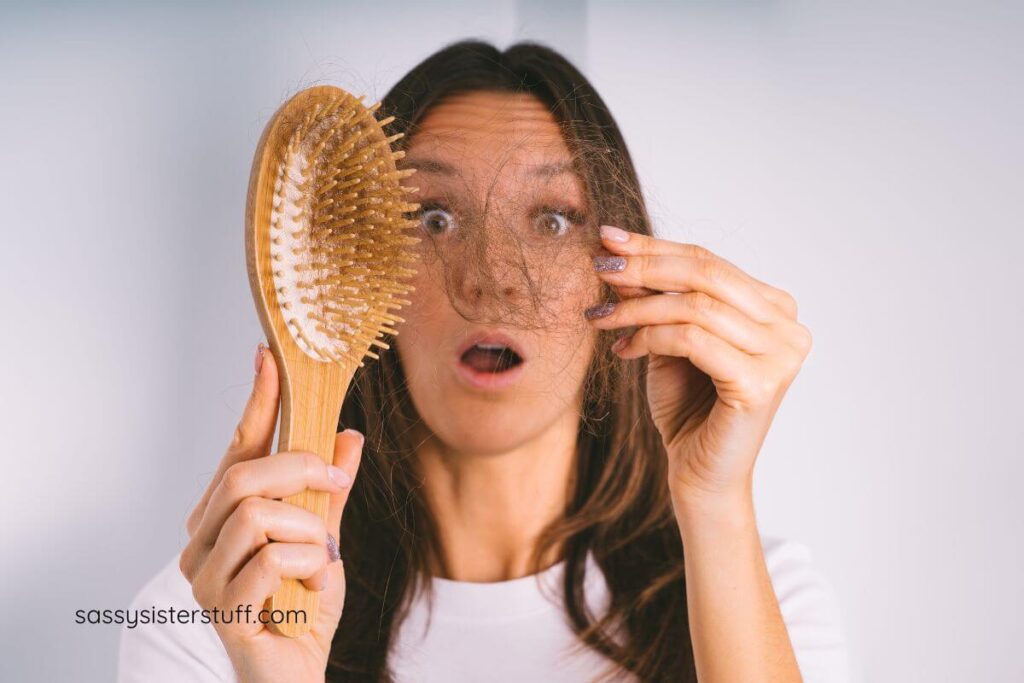 woman looking shocked at her hair brush when she sees so much hair loss in midlife.
